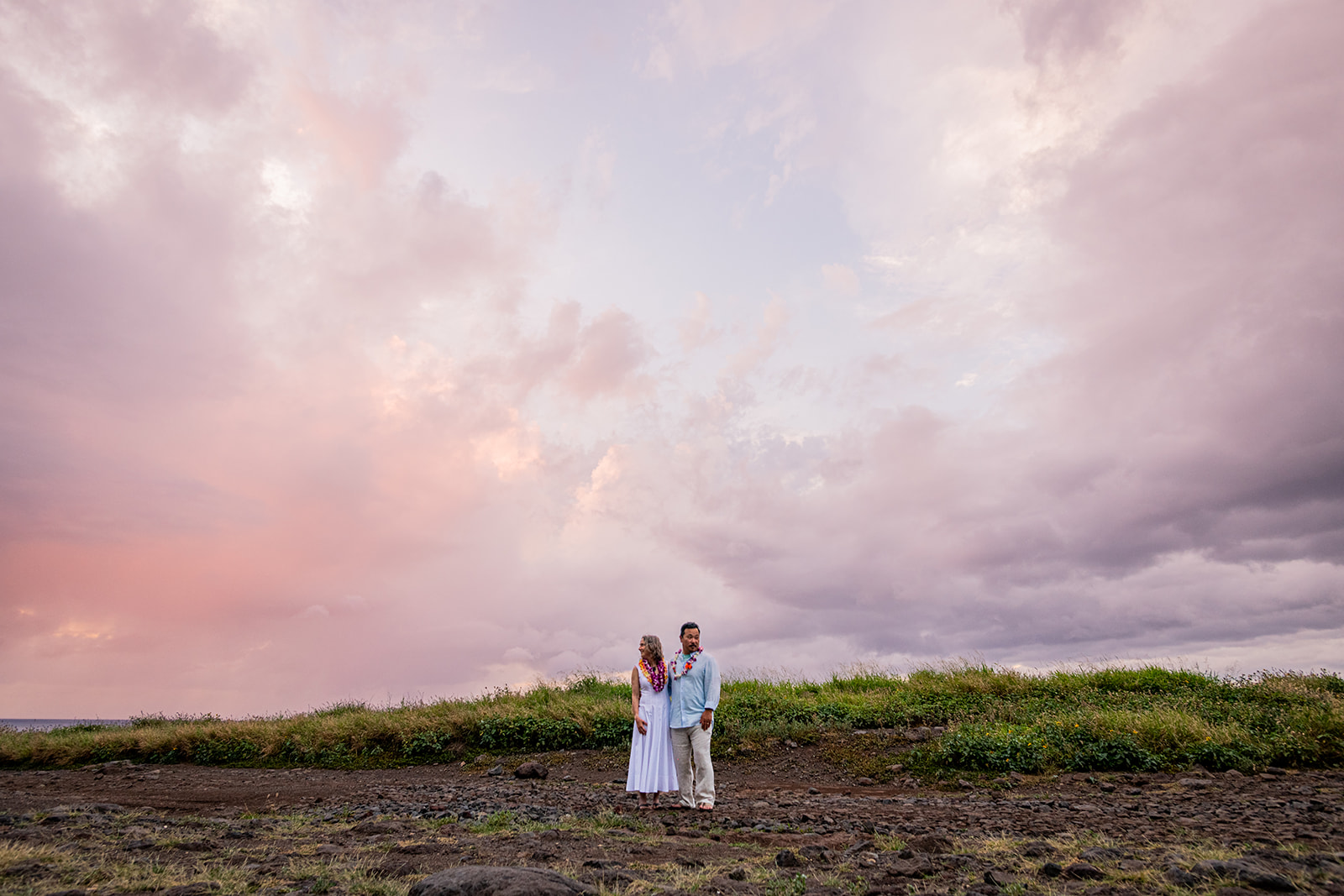 couple eloping under a pink sky at sunset
