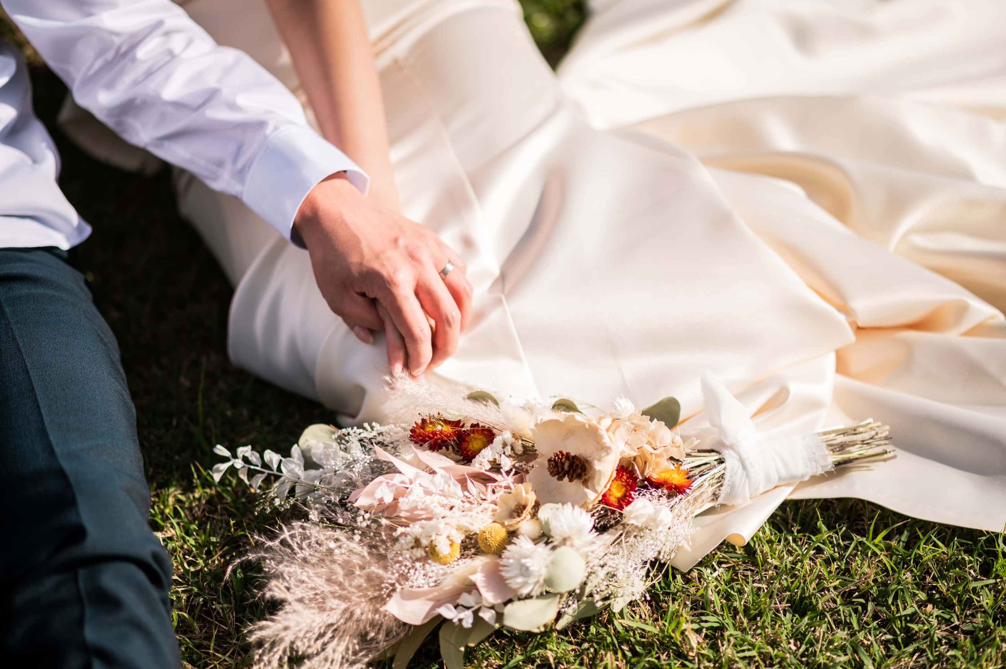 Photo of elopement couple holding hands sitting on a field of grass in Oahu