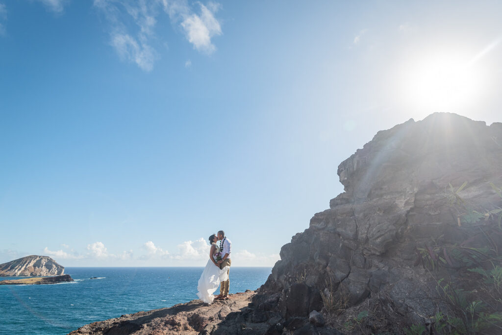 Bride and groom on a cliff by the ocean while they elope on Oahu, Hawaii