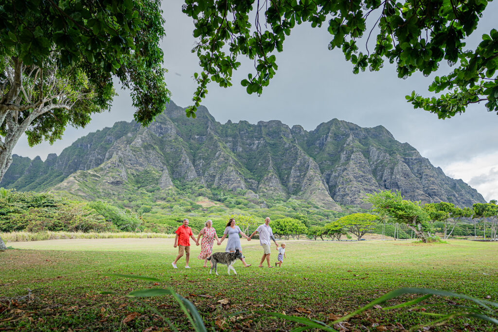 Family holds hands in front of the Ko'olau mountains in Kualoa area of Oahu's North Shore
